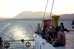 Andere Passagiere genießen den kühlen Wind auf See und betrachten den Sonnenuntergang