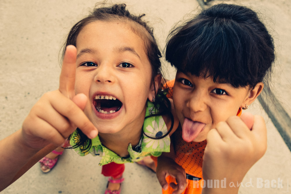 Zwei Mädchen, die mit frechen Gesten in die Kamera lachen. Samarkand, Usbekistan.