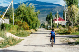 Junge mit Fahrrad in einem Wohnviertel in Karakol, Kirgistan