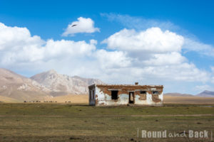 Eine alte Ruine am Ufer des Song Kul mit den Bergen im Hintergrund